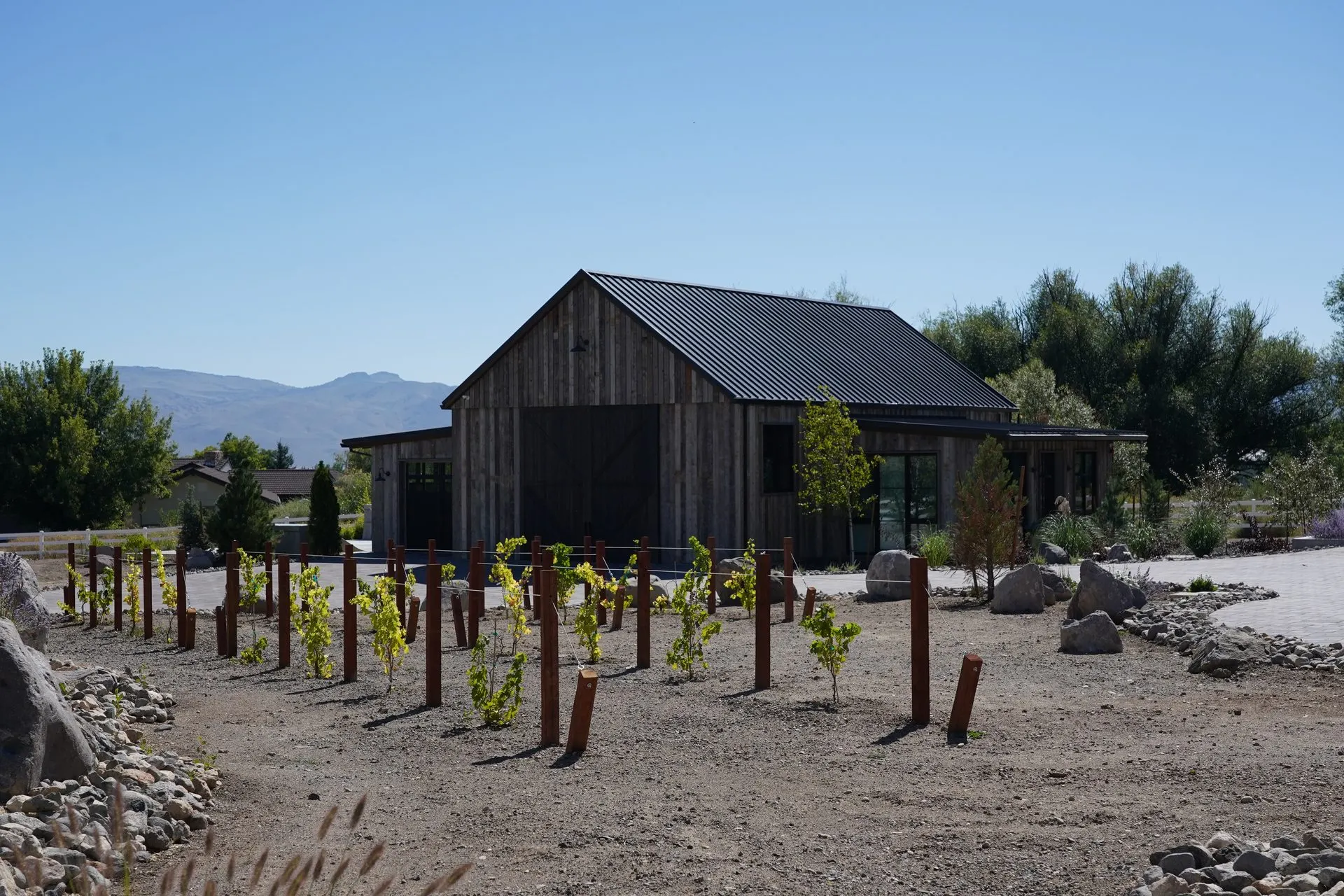 Barn-style custom home exterior with graded site and access drive