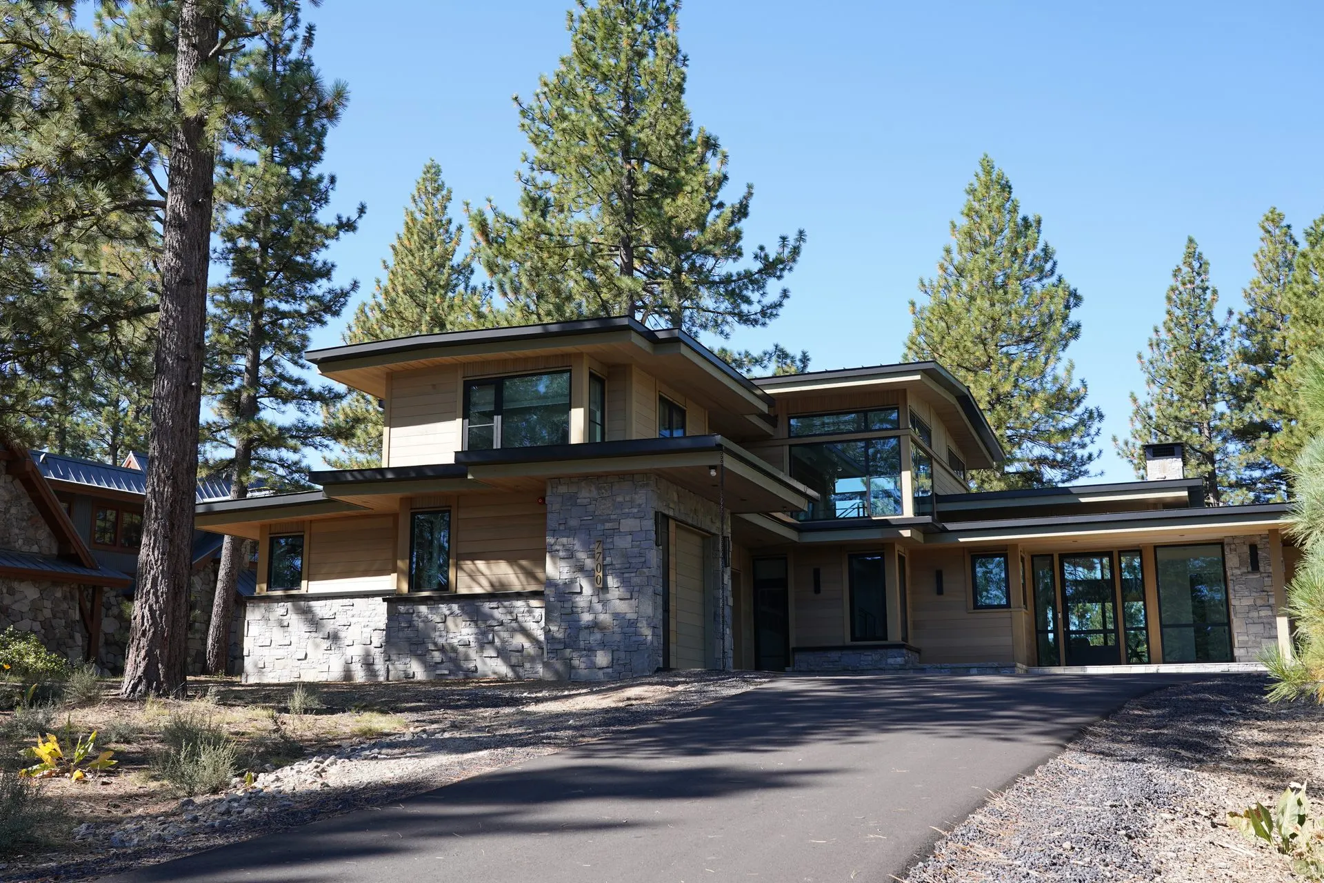 Stone-clad custom mountain home with graded driveway and site terracing