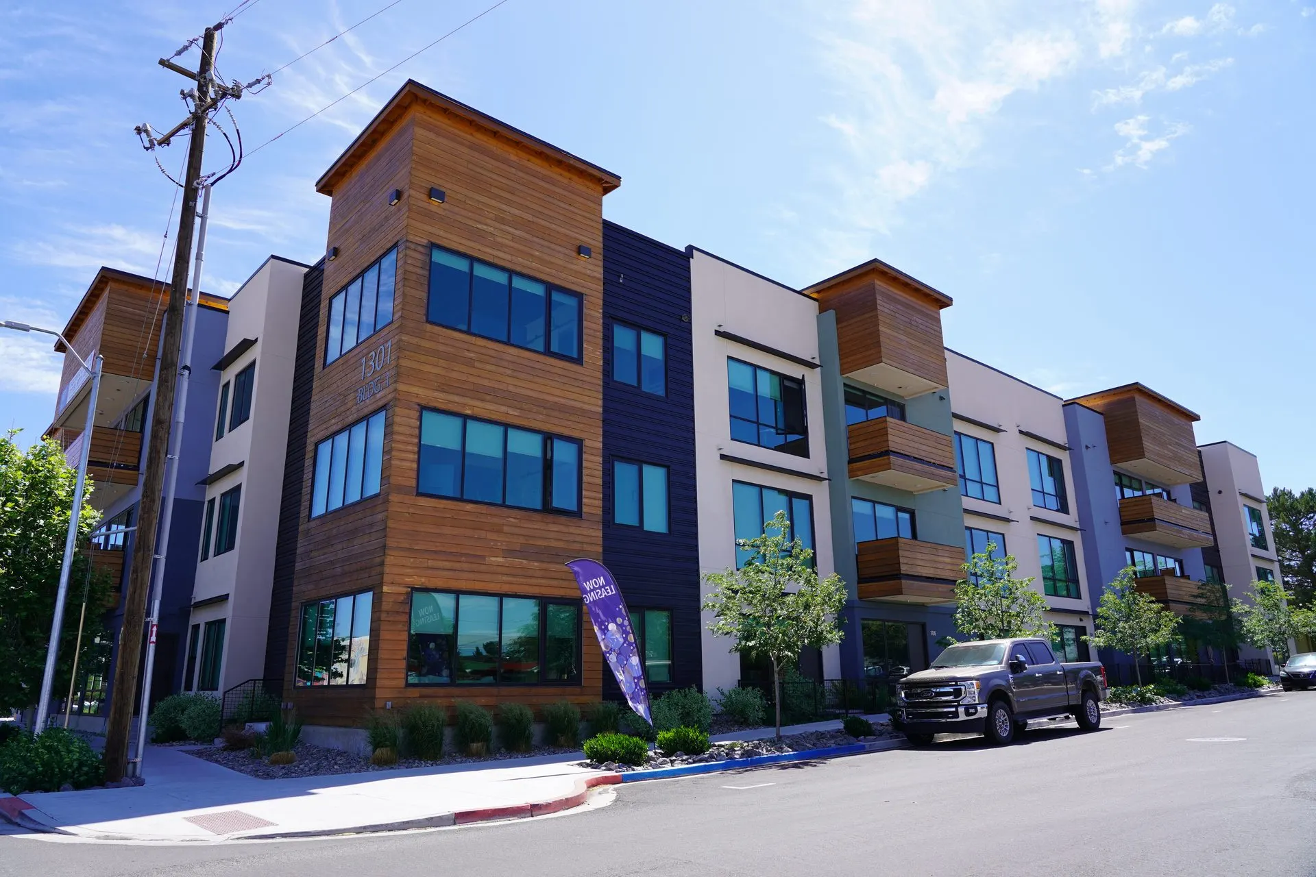 Modern apartment building exterior with street frontage, curb, and sidewalk improvements